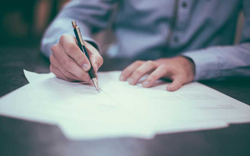 plan rapproché sur les mains d'un homme signant des documents administratifs à la Feebf