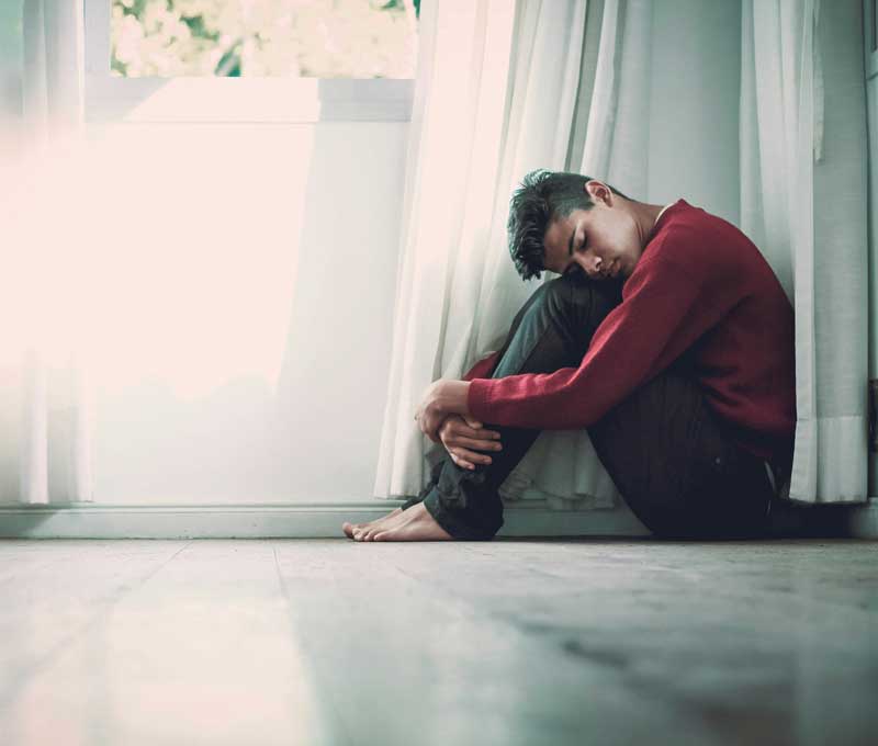 un jeune homme prostré par terre, l'air endormi, victime de burn-out