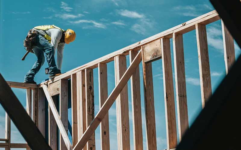 ouvrier en équilibre sur une poutre de bois, sur un chantier d'une église évangélique baptiste