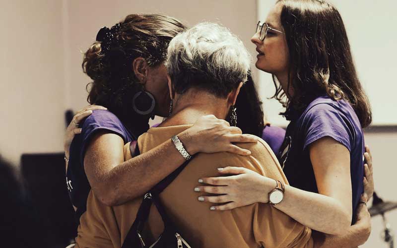 3 femmes de générations différentes priant et vivant la communion fraternelle dans un rassemblement chrétien